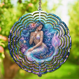 May include: A circular metal wind spinner featuring a detailed illustration of a mermaid with long flowing blue hair, a shimmering iridescent tail, and a seashell top, surrounded by coral, small fish, and pearls within a scalloped frame.