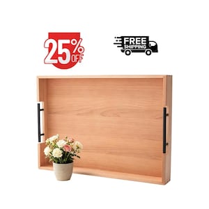 May include: A rectangular light brown wooden serving tray featuring a smooth grain finish and two vertical black metal handles attached to the sides. A small ceramic pot containing a bouquet of white and pink flowers sits inside the tray.