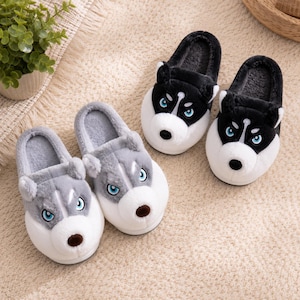 May include: Two pairs of plush slippers shaped like husky dog heads. One pair is black and white, and the other pair is grey and white. Each slipper features embroidered blue eyes, a soft snout, and small ears, with a fuzzy interior lining.