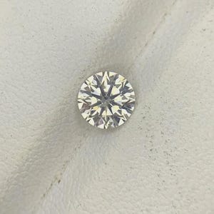 Peut inclure: Une pierre précieuse taille brillant ronde présentant un agencement complexe de facettes triangulaires et en forme de cerf-volant créant un motif en étoile symétrique. La pierre est incolore et transparente, avec des reflets lumineux nets.