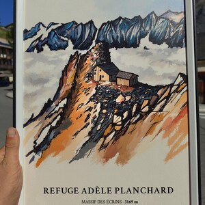 Peut inclure: Une impression encadrée illustrant le paysage de montagne du Refuge Adèle Planchard dans le Massif des Écrins à 3169 m. L'œuvre représente un petit refuge perché sur un pic rocheux aux tons orangés avec des montagnes bleutées en arrière-plan.