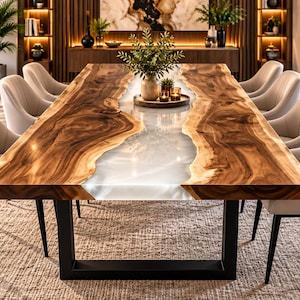 Op de afbeelding: Een rechthoekige eettafel met twee natuurlijke houten bladen met een centrale inleg van doorschijnende witte hars. De tafel wordt ondersteund door een zwart metalen U-vormig onderstel en is omringd door zes beige gestoffeerde stoelen.