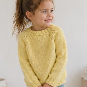 May include: A pale yellow long-sleeve knit sweater featuring a ribbed crew neckline, ribbed cuffs, and a ribbed hem. The sweater is constructed with a raglan sleeve design and a classic stockinette stitch pattern throughout the body and sleeves.