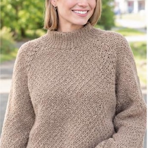 May include: A beige long-sleeve sweater featuring a mock neck collar and a textured diamond knit pattern. The garment is constructed with ribbed cuffs and a ribbed hem, showcasing a consistent neutral color throughout the entire knitted fabric.
