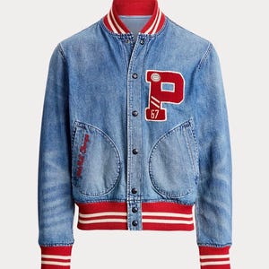 May include: A blue denim varsity jacket featuring a red and white striped ribbed collar, cuffs, and hem. The front has a large red letter P patch with the number 67, metal snap buttons, and two side pockets with red embroidered text on the right.