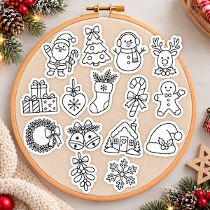 May include: A collection of fourteen black and white Christmas-themed stickers arranged on a circular wooden embroidery hoop. The designs include Santa Claus, a Christmas tree, a snowman, a reindeer, gifts, a heart ornament, a stocking, a candy cane, a gingerbread person, a wreath, bells, a house, a Santa hat, mistletoe, and a snowflake.