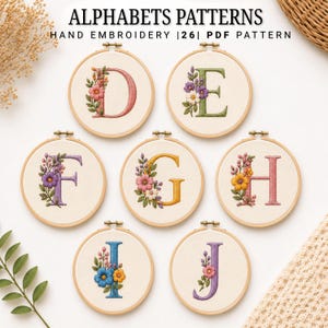 Op de afbeelding: Zeven ronde houten borduurringen met handgeborduurde letters D, E, F, G, H, I en J op witte stof. Elke letter is versierd met kleurrijke bloemenborduursels. De tekst ALPHABETS PATTERNS HAND EMBROIDERY 26 PDF PATTERN is zichtbaar in de afbeelding.