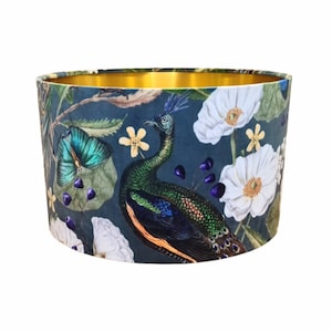 Peut inclure: Un abat-jour en velours bleu avec une bordure dorée et un imprimé de paon, de papillon et de fleurs.