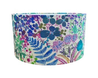 May include: A white lampshade with a colorful floral print featuring blue, pink, purple, and green flowers and leaves.