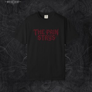 以下が含まれることがあります： 胸元にダークレッドのギザギザとしたスタイリッシュなフォントで「THE PAIN STAYS」というテキストがプリントされた、黒の半袖Tシャツ。クルーネックで標準的なフィット感があり、首の内側に小さな白いブランドラベルが付いています。