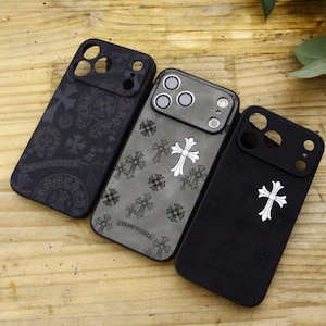 Puede incluir: Se muestran tres fundas rectangulares para smartphone. La funda de la izquierda es negra con un patrón de cruces tonales. La central es gris con un motivo de cruces blancas repetidas. La de la derecha es negra con una cruz blanca central.