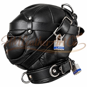Puede incluir: Una capucha de cuero negro con construcción de paneles múltiples, correas ajustables, herrajes de metal plateado y dos candados de la marca Master con cuerpos azules y plateados sujetos al lateral y al collar.