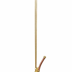 Pu&ograve; includere: Un gancio da parete in metallo dorato con una piastra di montaggio rettangolare verticale e un lungo braccio curvo. Una sottile catena dorata pende dal supporto superiore, collegata a un ornamento decorativo in metallo color rame e oro a forma di fischietto.