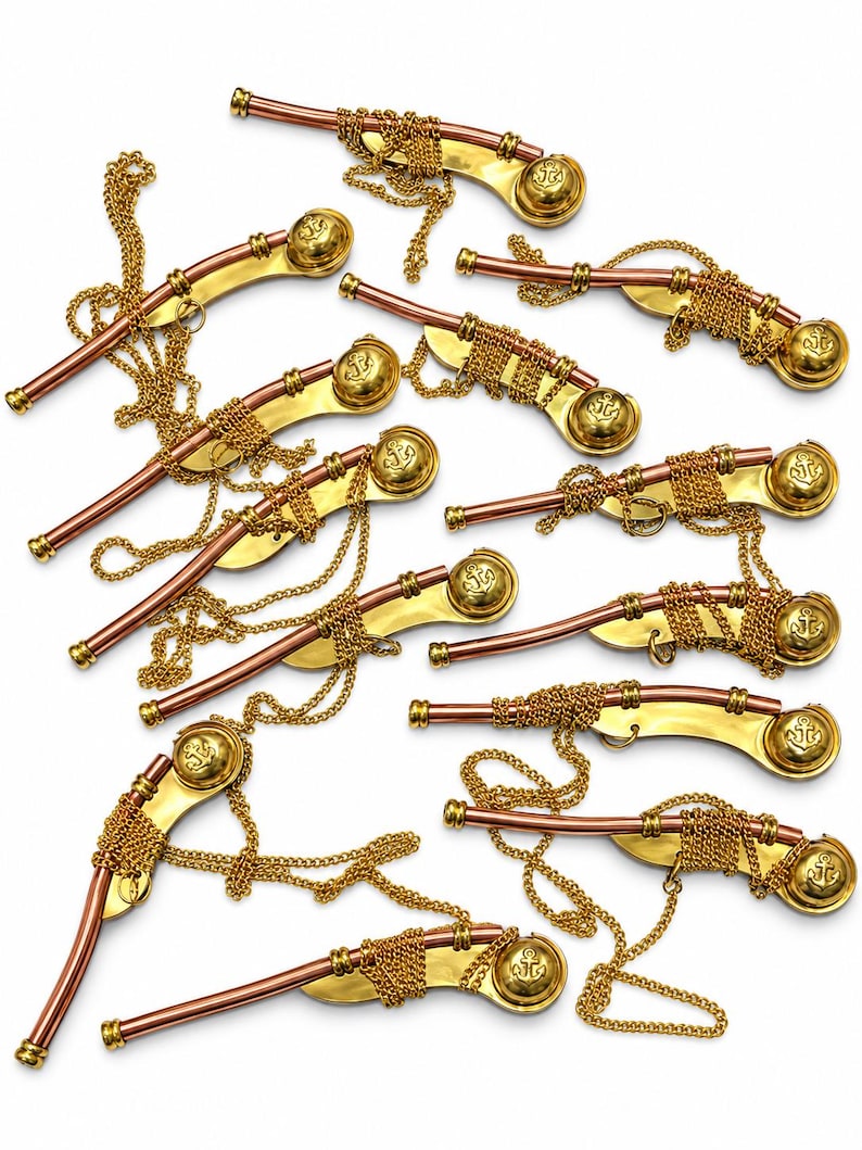 Pu&ograve; includere: Una collezione di dieci fischietti in metallo, ognuno caratterizzato da un tubo color rame e un corpo curvo color oro. Ogni fischietto include una catenella dorata e un'estremit&agrave; circolare con impresso un simbolo di ancora, disposti sparsi.