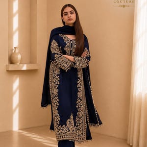 Könnte beinhalten: Ein dreiteiliges marineblaues Set bestehend aus einer langärmeligen Tunika, einer weiten Hose und einem passenden Dupatta. Die Tunika und die Hose sind mit goldener Stickerei an den Säumen und der Vorderseite verziert, inklusive KC KYORA COUTURE.
