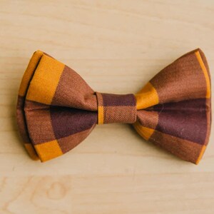 May include: A brown and orange plaid bow tie.