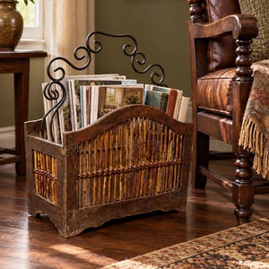 May include: A rectangular magazine rack constructed from dark brown wood and vertical bamboo slats, featuring a decorative black wrought iron handle with scrollwork details. The rack is filled with various books and magazines.