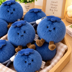 May include: A collection of round, blue plush blueberry keychains with soft, fuzzy textures. Each plush features a small, dark blue felt leaf on top, brown fabric legs, and a simple embroidered face with two black eyes and a small, curved smile.