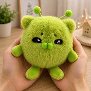 Peut inclure: Une peluche ronde vert citron avec une texture douce et duveteuse. Elle présente deux petites antennes avec des pompons au sommet, deux bras courts, deux jambes courtes et un visage brodé avec des yeux ovales noirs et deux petites joues rondes vertes.