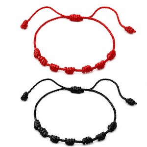 Peut inclure: Deux bracelets en cordon réglables, un rouge vif et un noir. Chaque bracelet présente une série de petits nœuds décoratifs régulièrement espacés le long de la bande circulaire et un mécanisme de fermeture coulissant avec des extrémités nouées.