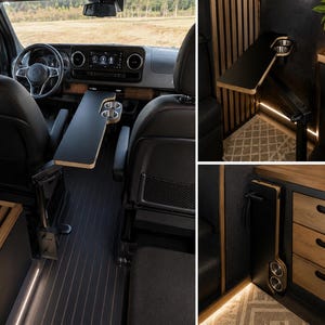 May include: A black, foldable swivel table with two integrated stainless steel cup holders, designed for vehicle interiors. The table features a smooth matte surface with exposed plywood edges and a sturdy black metal mounting arm.