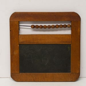 May include: A square wooden frame featuring a dark chalkboard surface with the letters A, B, and C faintly written in chalk. Above the chalkboard, a single horizontal metal rod holds ten small, round, brown wooden beads for counting.