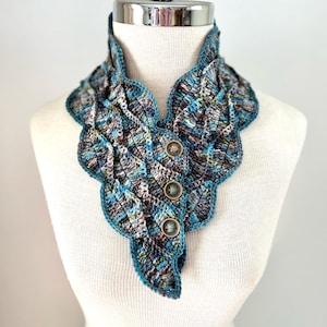 May include: A crocheted neck warmer with a blue, green, and brown color scheme. The warmer has a scalloped edge and features three buttons.