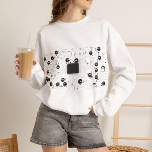 May include: A white long-sleeve sweatshirt featuring a black graphic print of a central computer chip connected to circuit board lines, surrounded by numerous small, round, fuzzy-looking creatures interacting with the electronic components.