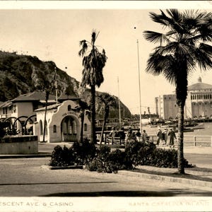 Peut inclure: Une carte postale vintage sépia montrant Crescent Avenue et le Casino sur l'île de Santa Catalina, en Californie. La scène présente des palmiers, une fontaine, un bâtiment avec des entrées voûtées et le grand Casino près de l'eau.