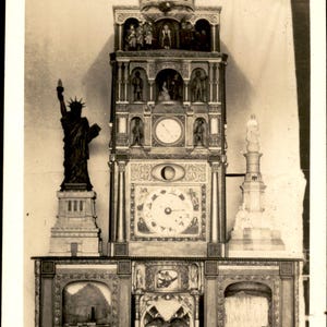 Peut inclure: Une photographie en noir et blanc d'une horloge historique haute et ornée, avec une statue de la Liberté à gauche, un cadran central et une base avec des paysages. Le texte en bas indique : Collins' Historical Clock, George's Mills, N.H.