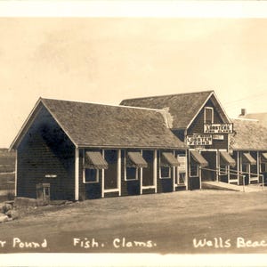 Peut inclure: Une carte postale vintage sépia montrant un bâtiment en bois nommé Wells Beach Lobster Pound avec des auvents rayés sur les fenêtres. Le texte indique Lobster Pound, Fish, Clams et Wells Beach Me. Une voiture est garée près de l'entrée.