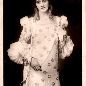 Puede incluir: Una fotografía vintage en tono sepia de una persona con un vestido de manga larga con motivos florales, mangas abullonadas y un collar de perlas. El texto en la parte inferior dice: 125. MISS MARGARET HALSTAN, PERCY GUTTENBERG MANCHESTER IN "OTHELLO." COPYRIGHT.