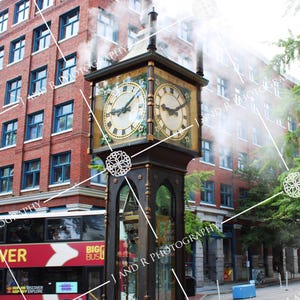 May include: A dark metal steam clock with four clock faces featuring Roman numerals, emitting white steam from its top. The clock stands on a street corner in front of a multi-story red brick building with blue window frames and a red tour bus.