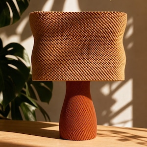 May include: A table lamp with a textured, light brown, rectangular shade and a matching orange, tapered, cylindrical base. The entire surface of both the shade and the base features a fine, uniform, cross-hatched, or grid-like pattern.