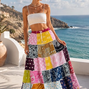 May include: A white strapless crop top with a textured finish paired with a long, high-waisted patchwork skirt. The skirt features a variety of colourful fabric squares in shades of yellow, pink, blue, and dark purple, each with distinct floral and geometric patterns.