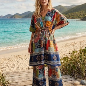 Può includere: Un completo a due pezzi composto da una tunica con scollo a V, maniche corte e coulisse in vita, abbinato a pantaloni a gamba larga. Entrambi i capi presentano un vivace motivo patchwork multicolore con disegni geometrici blu, rossi, gialli e verdi.
