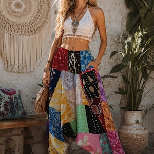 May include: A white crochet halter top with a fringe hem paired with loose-fitting, high-waisted harem pants featuring a multi-colored patchwork design. The pants display various floral, paisley, and geometric patterns in shades of red, blue, yellow, and pink.