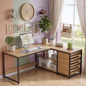 May include: An L-shaped desk with a light wood grain surface and a black metal frame. The desk features a side unit with four wooden drawers and open shelving for storage. A computer monitor, keyboard, and mouse sit on the desk surface.