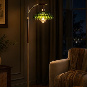 May include: A floor lamp featuring a gold-toned metal base and pole with a dark wood accent section. The lamp has an arched top arm holding a scalloped, translucent green glass shade with a single exposed light bulb emitting a warm glow.