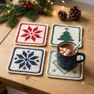 Puede incluir: Cuatro posavasos cuadrados de ganchillo en hilo color crema con distintos patrones navideños en rojo, verde oscuro y azul marino. Uno de los posavasos sostiene una taza de cerámica azul oscuro con chocolate caliente, nubes y una cuchara.