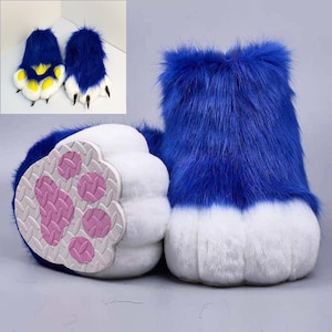 May include: A pair of plush animal paw boots covered in long, vibrant blue faux fur. The boots feature white faux fur toes and a textured, light grey sole with a pink paw pad design. The inset shows the boots from a top-down perspective.
