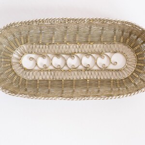 May include: A silver wire basket with a decorative design. The basket is oval shaped and has a woven pattern.