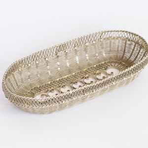 May include: A silver wire basket with an oval shape and decorative details. The basket is made of thin wire and has a delicate, intricate design.