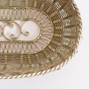 May include: A silver wire basket with a decorative design. The basket is oval shaped and has a woven pattern.