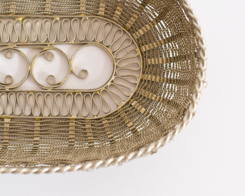 May include: A silver wire basket with a decorative design. The basket is oval shaped and has a woven pattern.
