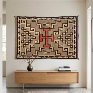 Peut inclure: Une tenture murale tissée rectangulaire présentant un motif géométrique dans des tons de beige, brun foncé, noir et rouge. Le design comprend une croix rouge centrale entourée de bordures en escalier et de petits accents triangulaires.