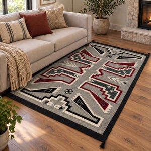 May include: A rectangular area rug featuring a gray background with a repeating geometric pattern in black, white, and deep red. The design includes stepped shapes, arrow motifs, and a solid black border with small tassels at the corners.
