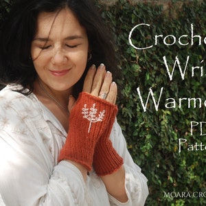 May include: A woman wearing a white shirt and a pair of orange crochet wrist warmers with a white embroidered design. The text "Crochet Wrist Warmer PDF Pattern" is displayed on a green background. The text "MOARA CROCHET" is displayed at the bottom of the image.