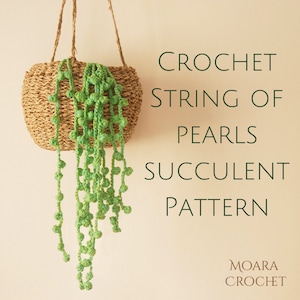 Op de afbeelding: Een groene gehäkelde parelketting succulent hangend aan een geweven mand. De tekst "CROCHET STRING OF PEARLS SUCCULENT PATTERN" is in zwarte tekst op een lichtbeige achtergrond geschreven. De tekst "MOARA CROCHET" is in bruine tekst in de rechterbenedenhoek van de afbeelding geschreven.