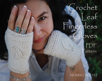 May include: A pair of white crochet fingerless gloves with a leaf pattern. The gloves are being worn by a person with a turquoise ring on their finger. The text "Crochet Leaf Fingerless Gloves PDF Pattern" is visible in the image. The text "MOARA CROCHET" is also visible in the image.